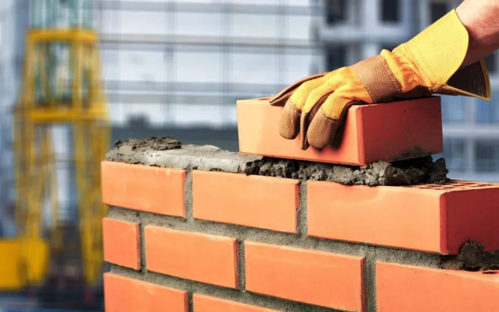 Masonry worker laying bricks and mortar on a construction site, focusing on precision and craftsmanship.